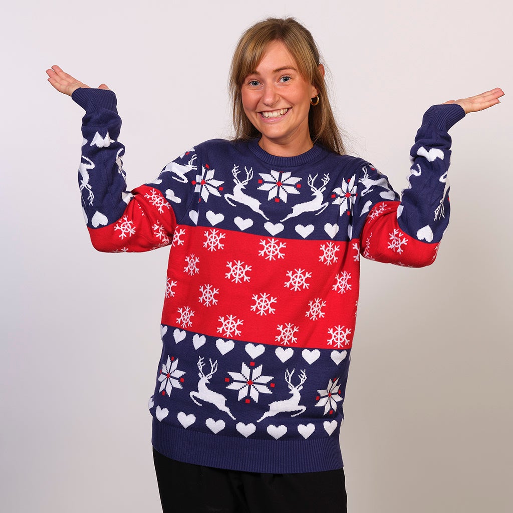 En kvinde iført en rød og blå julesweater med snefnug og rensdyr.